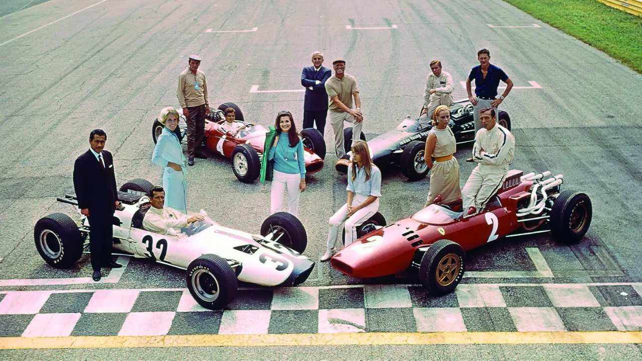 a group of men and women posing by racecars
